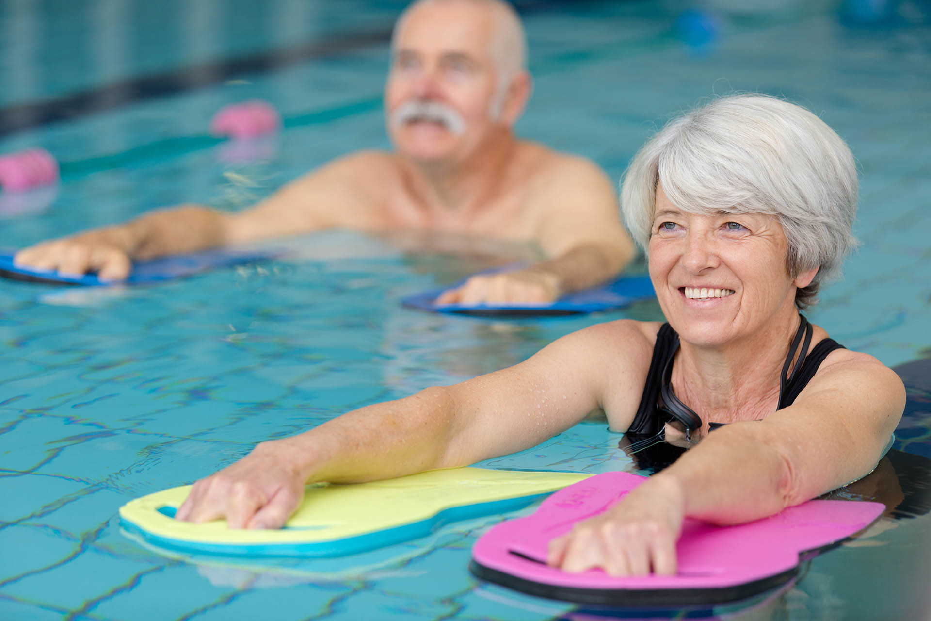 Ältere Menschen nehmen an einer Wassergymnastik im Schwimmbad teil.