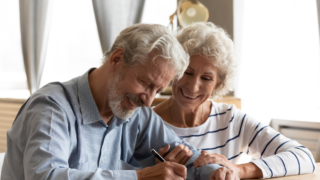 Zwei Personen, die auf einen Zettel schauen und grinsen.